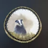 Aquarelle originale de Renaud Prégaldiny artiste peintre aquarelliste. Portrait d'un blaireau, animal paisible représenté dans son environnement et présenté dans un cadre rond en baguette de bambou.
